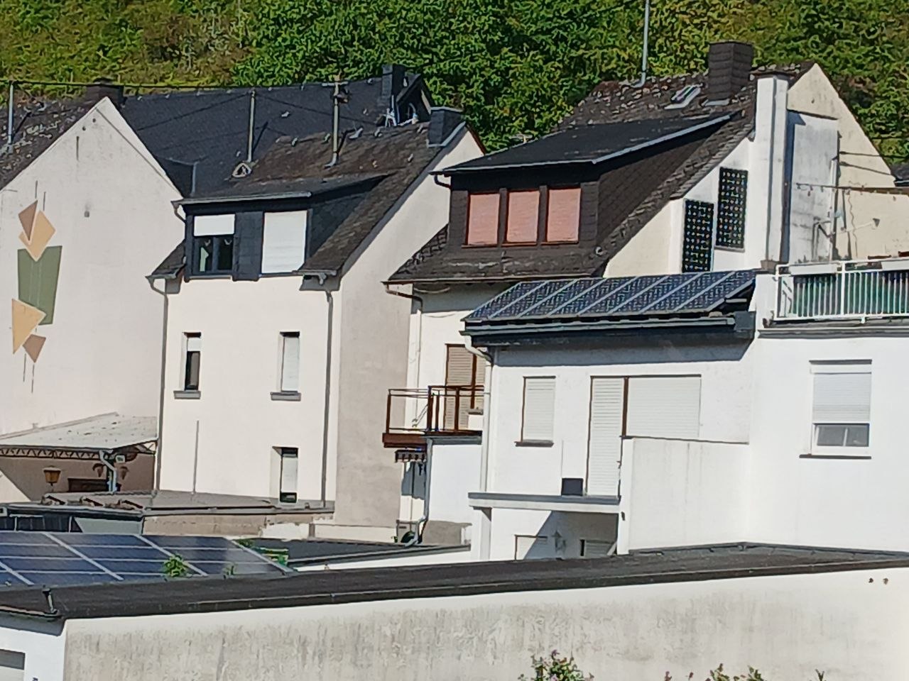 Wohnhäuser an der Mosel mit geschlossenen Rollläden und Jalousien bei strahlendem Sonnenschein